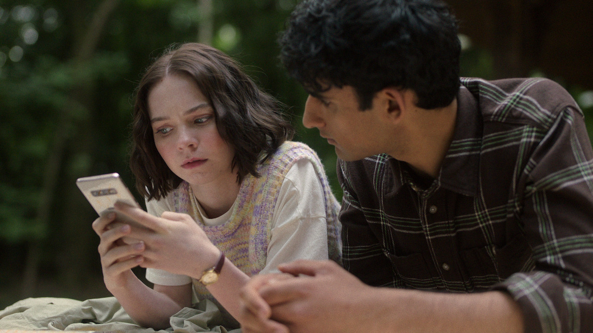 Pip (Emma Myers) y Ravi (Zain Iqbal) mirando un teléfono móvil.